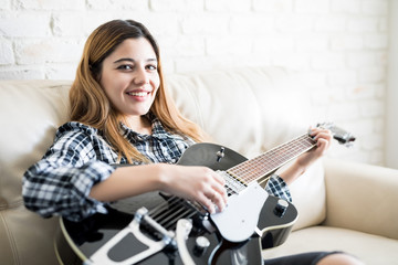 Obraz na płótnie Canvas Woman enjoying playing guitar at home