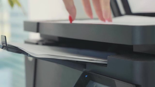 Close-up of woman using photocopier for document copying at office