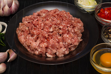 Raw meat beef in a plate with spices on a black cutting board. Fresh stuffing.