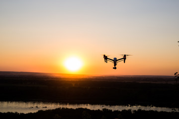 silhouette of drone, quadrocopter with photo camera flying in the sky.