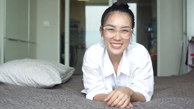 close up portrait young Asian woman laughing shows sign symbol OK on bed. attractive millennial girl looking at the camera smiling 