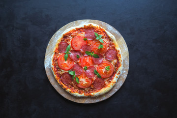 Home-made pepperoni pizza on a black table.