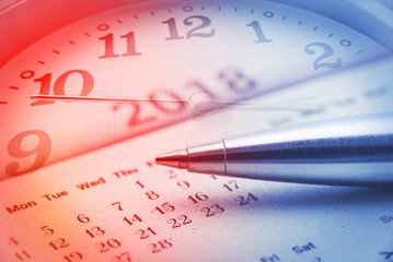 Calendar planner for year 2018 concept : Blue metal pen on a paper desk calendar with analog clock...