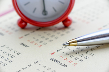 Calendar planner / timetable or schedule arrangement concept : Blue metal pen on a calendar with a...