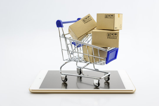 Online shopping or ecommmerce and international freight service concept : Paper boxes with logos in a shopping cart on a white smart mobile phone device. Consumers always shop goods using the internet