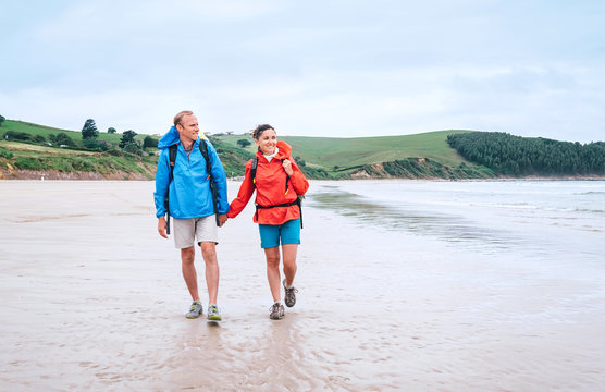 Couple travelers walk on the coast of Biskay Bay in North Spain, part of camino del Norte famous piligrims route