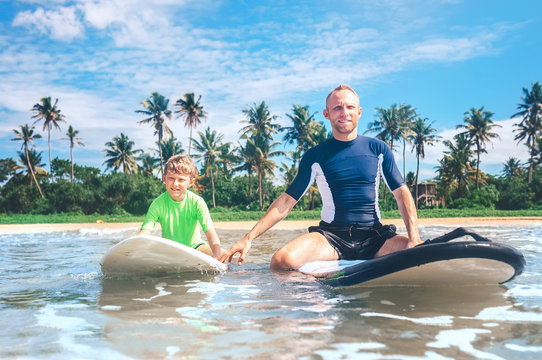 Father and son sit on surfboards. First surfing lessons