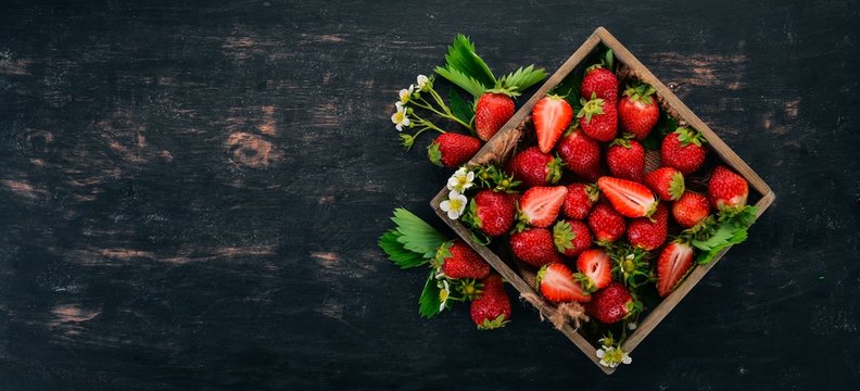Fresh strawberries in a wooden box. On a wooden background. Top view. Copy space.