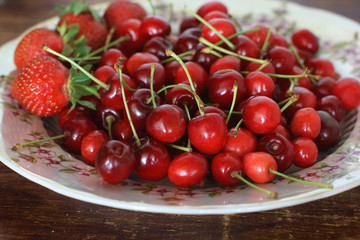 Strawberries and sweet cherries. Berries close-up on a plate