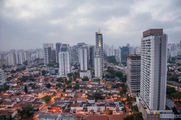 Naklejka premium View of the city skyline in the early morning light with houses and buildings under cloudy skies in the city of São Paulo. The gigantic city, famous for its cultural and business vocation.