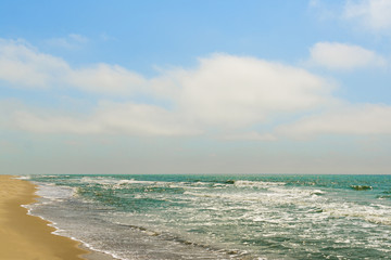 Diagonal composition of sand beach shore with the blue sea