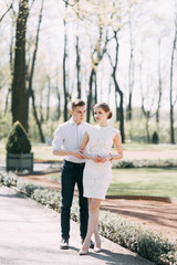 Obraz premium Beautiful young couple in the Park on a Sunny day, loving and happy. Walk and laugh together. Pre-wedding shooting in nature. Elegant style in clothes like celebrities