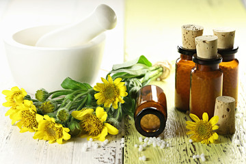 homeopathic arnica pills in brown bottles on wooden background