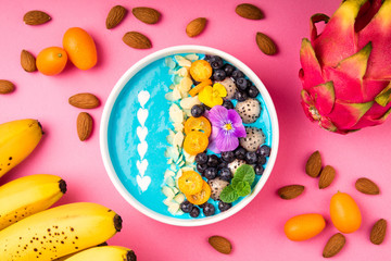 Smoothie bowl with fruits, berries, nuts and flowers. Tropical healthy smoothie dessert. Healthy breakfast, vegetarian food, lunch concept. Top view, flat lay