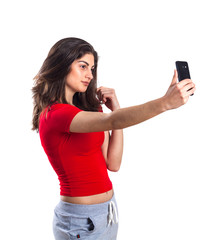 Cheerful attractive young sportswoman using mobile phone over white background