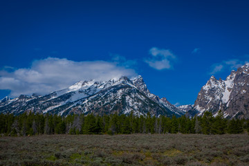 Fototapeta premium Beautiful landscape of the Grand Tetons range and peaks located inside the Grand Teton National Park, Wyoming, with house mountain covered with snow in the horizont