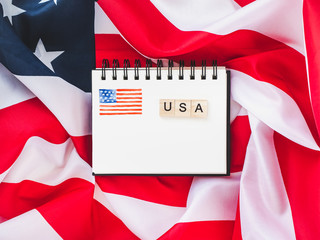 Notepad with blank page, wooden letters of the alphabet in the form of the word US on the...