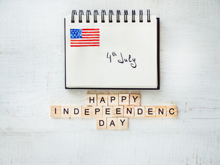 Notepad with the inscription 4th of July on a white, wooden, vintage table. Preparation for the Independence Day. Top view, close-up. The concept of an independent, strong country and nation
