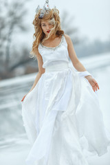 Fototapeta na wymiar The Snow Queen. Young beautiful girl, blonde, in the image of a snow queen, on ice of a frozen river