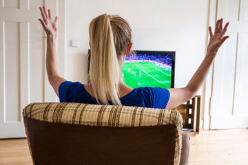 Attractive young woman watching a world cup football / soccer match on TV