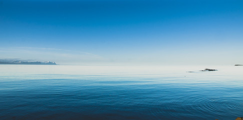 Icelandic landscapes full of green grass, sea and blue sky.