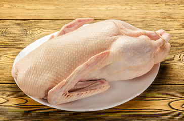 The duck is raw, ready to cook. Gutted carcass of a bird. Wooden table. Recipe preparations....