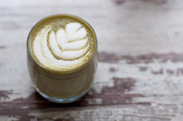 Trendy multicolored lattes. Top view of hot green tea milk or avocado or matcha tea taste with latte art in a cup on wood table. Beautiful foam, glass cups, stylish toning, space for text.