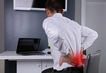 Business man suffering from back and neck pain in an office. Incorrect sitting posture problems,...