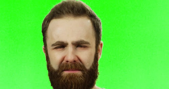 Close Up Of The Very Sad Man With A Beard Crying And Being Upset On The Green Screen. Chroma Key.