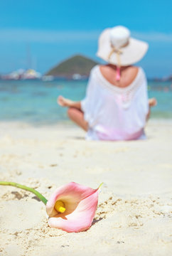 Calm lady meditating on a beach, beautiful flower