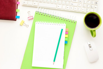 white Desk, green notebook  lies on the desk, office supplies, Cup of coffee, pensil, keyboard, white background with copy space, for advertisement, top view