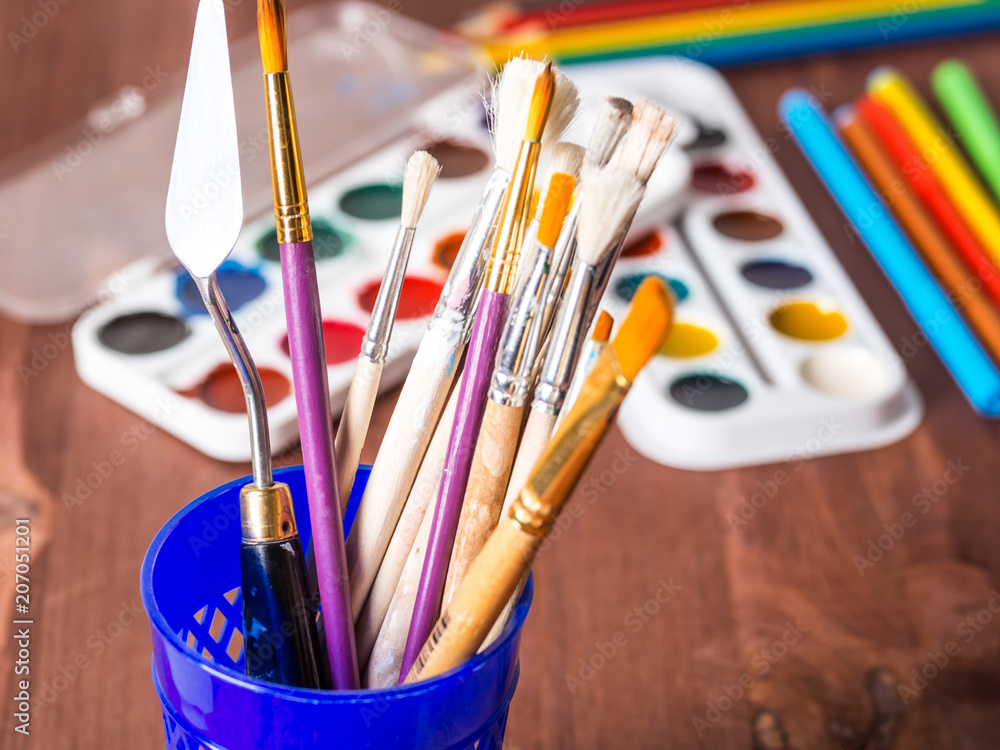 Wall mural artistic brushes in a cup close-up against a background of watercolor sets