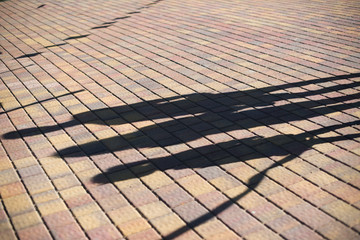 Long shadows of people on the sidewalk tiles in the urban environment at the dawn or dusk