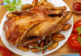 Roast duck on a white platter. Ready to serve poultry. Table setting. Roasted duck on the grill.