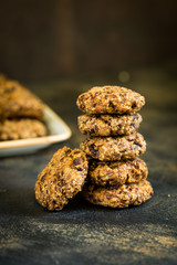 Healthy granola cookies stack, fitness energy food made of oats, dry fruits, seeds and grains, energy bar cookies on dark rustic background, copy space