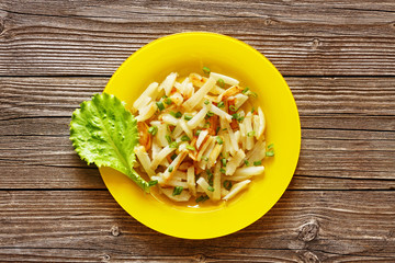 Fried potato in a plate on a wood background from above