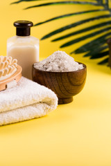 Fototapeta na wymiar Spa bath setting, sea salt in wooden bamboo bowl, soap, towel, body lotion, Asian skin care
