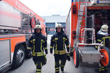 Feuerwehrmänner am Löschfahrzeug in Schutzausrüstung // Firemen at the vehicle in front of a fire station