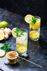Lemon fruit lime slices caipirinha from Brazil, lemonade mint ice cubes in cold glasses on dark background, alcoholic mojito cockail ice tea green mint leaves, brown sugar spoon, copy space