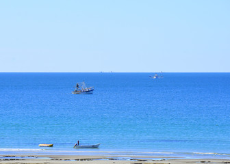 Obraz premium Small fishing boat on a beautiful ocean near the beach.