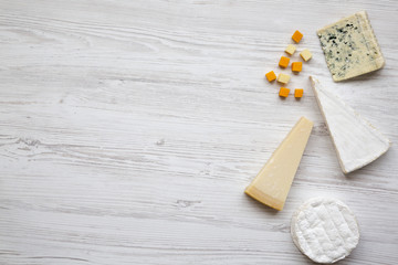 Set of different cheese on a white wooden background with copy space, top view. Food for wine. Flat lay, from above.