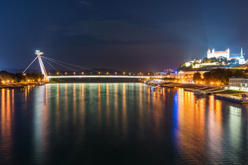 Fototapeta na wymiar Bratislava, Slovakia May 23, 2018: Night view on new bridge in Bratislava with castle on right side and lights reflection on Dunaj river.