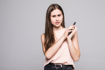 Portrait of a confused asian businesswoman covering mobile phone with palm while talking isolated over white background