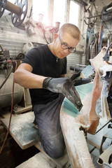 cute guy in glasses shpaklyuet repair area of ​​the car's wing in the garage