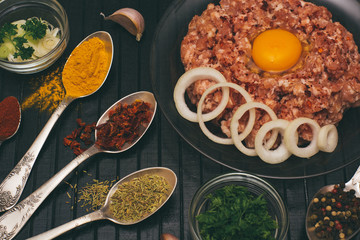 Raw meat beef in a plate with spices on a black cutting board. Fresh stuffing.