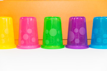 colorful plastic cups of lemonade on a white background. utensils for a picnic and travel
