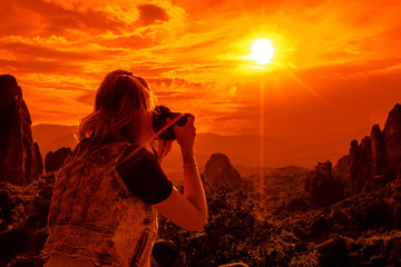 A travel photographer takes pictures of the spectacular monasteries of Meteora at sunset. Meteora is an area of Central Greece with several monasteries built on top of natural sandstone rock pillars.