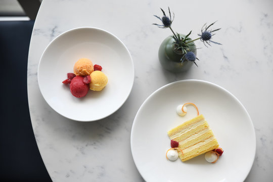 Sorbet with raspberries and yellow sponge cake slice on plates