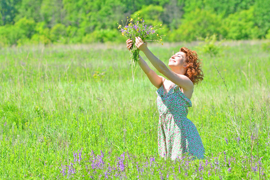 Beautiful and cheerful girl with a bouquet rejoices in the summer