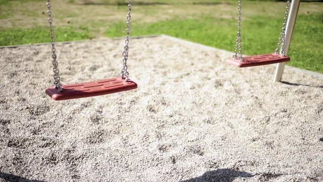 Abandoned empty swings swaying in the wind at children playground outdoors